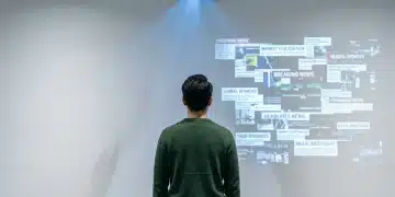 Unlocking Your Potential: A Beginner's Guide to News, Education, Benefits, and Finance An individual in a green sweater, viewed from behind, analyzing fragmented digital news projections on a white wall, representing critical news consumption.